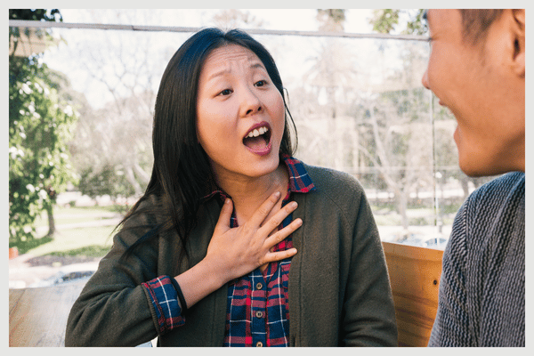 woman holding hand to chest talking